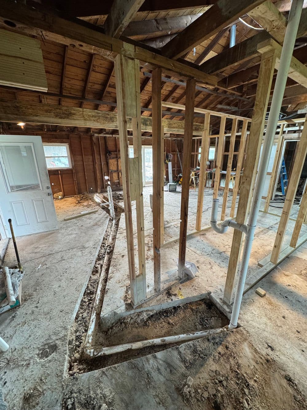 Interior of a home under construction, showcasing exposed wood framing and plumbing installation.