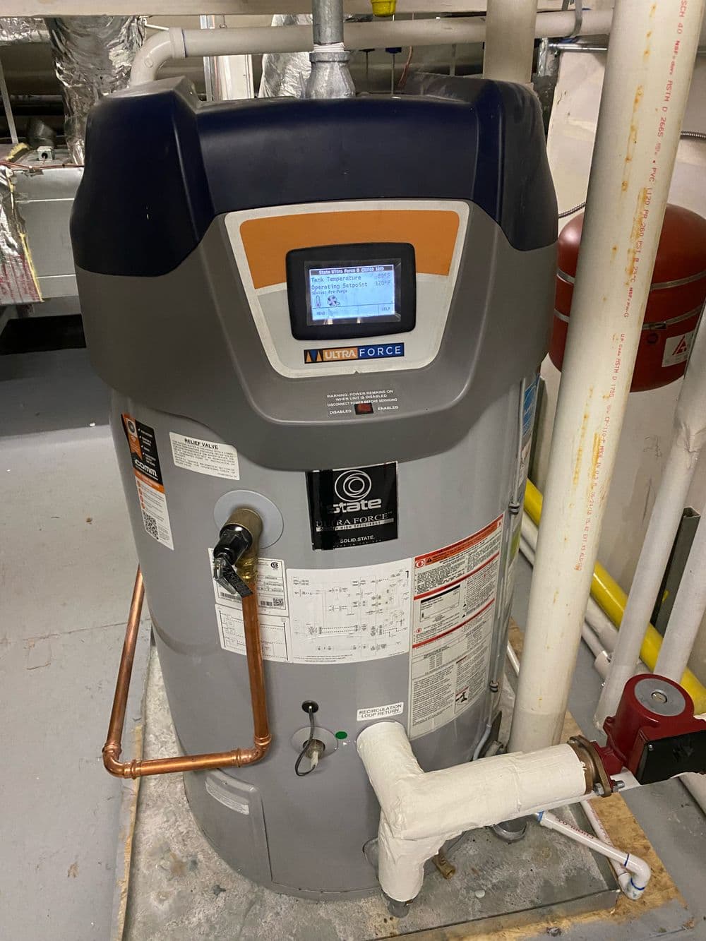 State water heater with digital display and copper piping in a utility room.