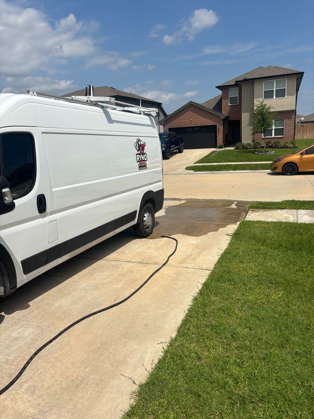 Ryno Services van parked in driveway of suburban home on a sunny day with clear skies.