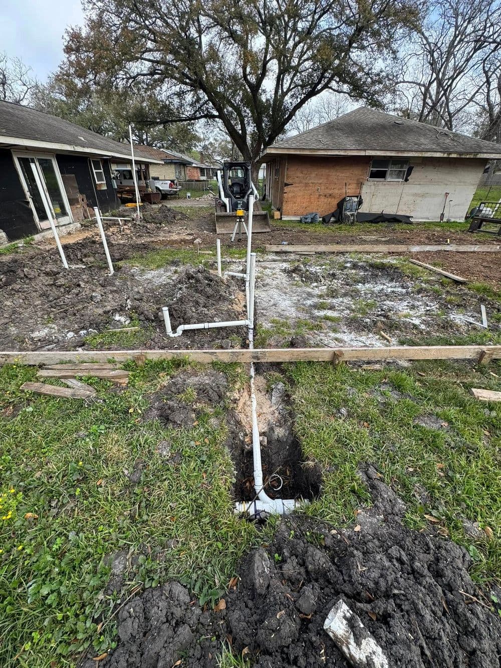 Construction site with trench and PVC pipes ready for foundation installation.